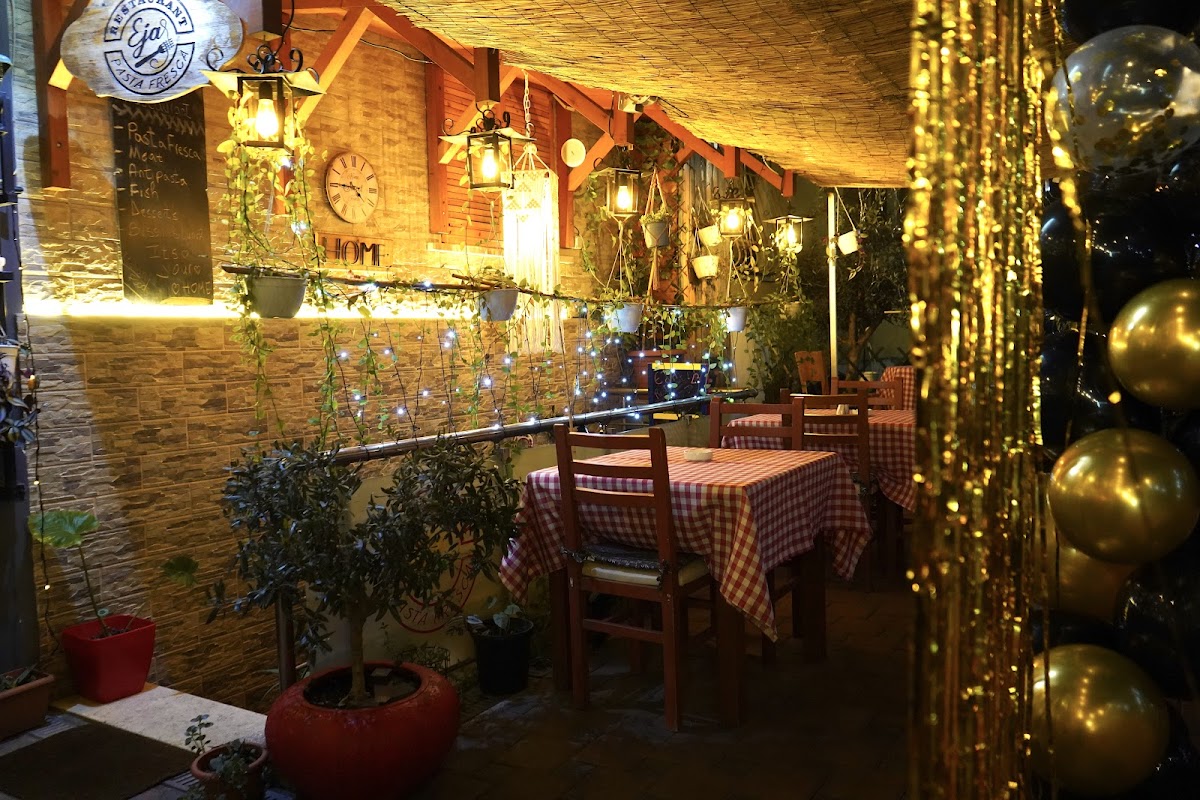 Eja interior with warm string lights and red-checkered tables